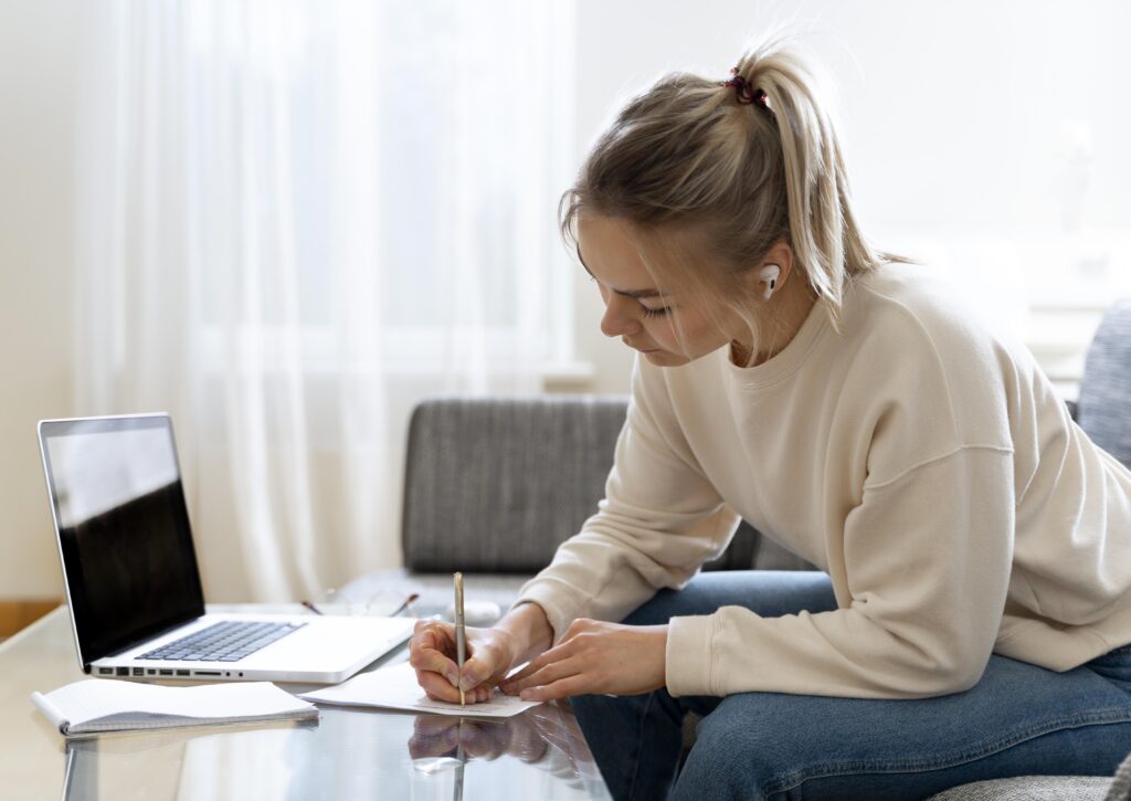 Conheça a certificação internacional de proficiência GRE l Mulher escrevendo com fones de ouvido l IP Schoo