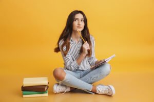 TOEFL x Cambridge: qual certificação escolher? | Retrato de uma jovem pensativa fazendo anotações | IP School
